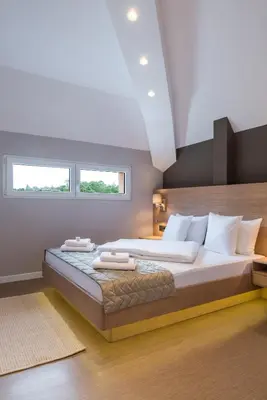 a bedroom with a large bed and two windows at Emilia Lux Rooms in Vrnjačka Banja