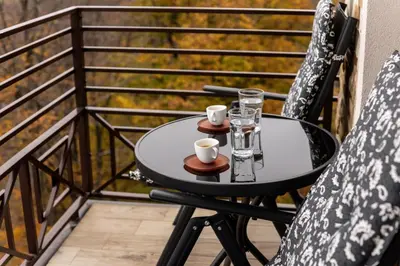 a small table on a balcony with two mugs and glasses at Apartman Stankovic Milmari Resort in Kopaonik