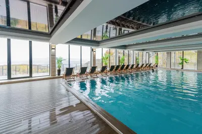 a swimming pool with chairs in a building with windows at Apartman Stankovic Milmari Resort in Kopaonik