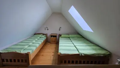 two beds in a attic bedroom with a window at Apartman 202 in Kopaonik