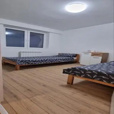 a room with two beds and a wooden floor at Iznad oblaka B09 in Kopaonik