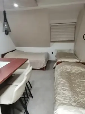 a room with two beds and a desk and a table at Tina Kop Apartments, Kopaonik in Kopaonik