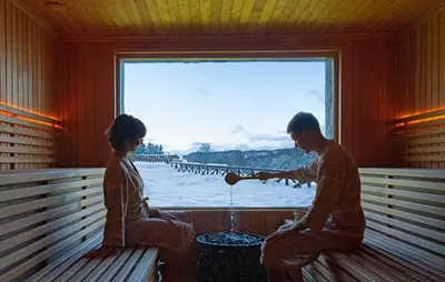 a man and woman sitting on a bench in front of a window at Apartmani BOŠ in Cajetina