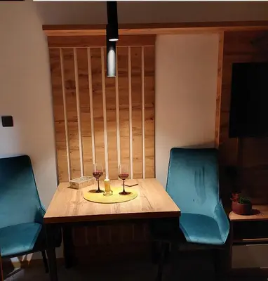 a table with two glasses of wine and two chairs at Nela apartmani (u hotelu Djina) in Kopaonik