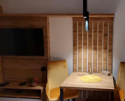 a dining room with a wooden table and a television at Nela apartmani (u hotelu Djina) in Kopaonik