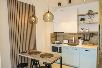 a kitchen with white cabinets and a table with stools at Milmari Apartments Pahulja N Lux in Kopaonik