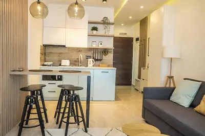 a kitchen and living room with a couch and bar stools at Milmari Apartments Pahulja N Lux in Kopaonik