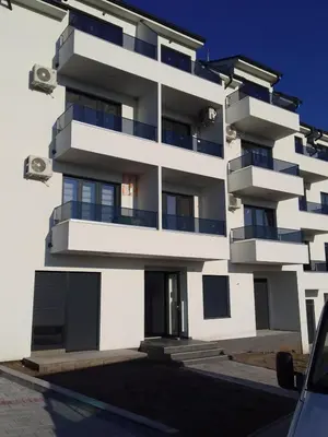 a white building with balconies and a car parked in front at Apartman Katarina in Soko Banja