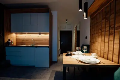 a kitchen with a wooden table with plates and wine glasses at Lux studio Andrej A43 Hotel Djina in Kopaonik