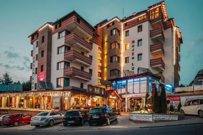a large building with cars parked in a parking lot at Apartman B 8 - Lapčević u zgradi MUJEN LUX, Kopaonik in Kopaonik