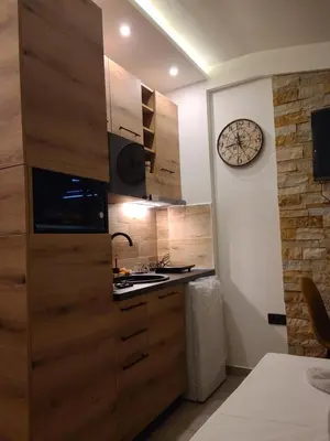 a kitchen with wooden cabinets and a clock on the wall at Kopaonik Milmari & Spa N Lux 90 in Kopaonik
