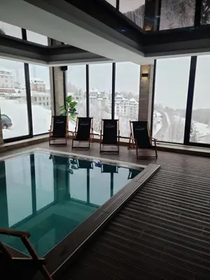 a swimming pool in a building with chairs and windows at Kopaonik Milmari & Spa N Lux 90 in Kopaonik