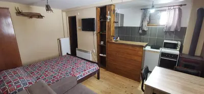 a bedroom with a bed and a kitchen with a table at Konak Šarac in Crni Vrh