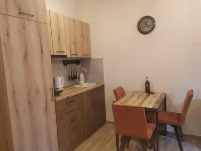 a kitchen with wooden cabinets and a table with chairs at Golden Mountain A75 NLux Milmari in Kopaonik