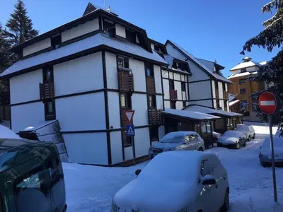 a snow covered building with cars parked in front of it at MR. O Apartments Kopaonik in Kopaonik