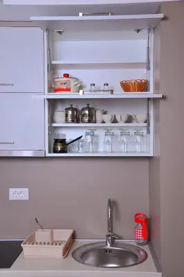 a kitchen counter with a sink and shelves with dishes at Apartman A20B in Kopaonik