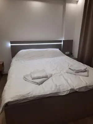 a bed with white sheets and two towels on it at Apartman A20B in Kopaonik