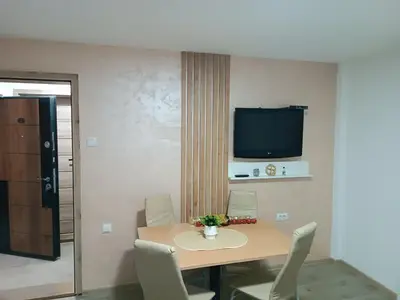a dining room table with chairs and a tv on the wall at Apartmani Moskva in Kopaonik