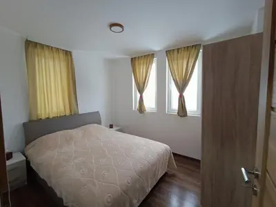 a bedroom with a bed and two windows at Apartmani Moskva in Kopaonik