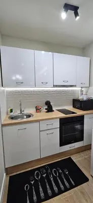 a kitchen with white cabinets and a sink and a kitchen rug at Apartman Vukota 2 Pirot in Pirot
