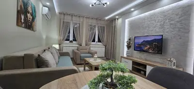 a living room with a couch and a tv on a wall at Apartman Vukota 2 Pirot in Pirot