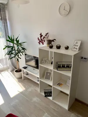 a white book shelf in a living room with a clock at Apartman-Stefanovic in Vranje