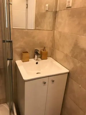 a bathroom with a white sink and a shower at Apartman Relax in Niš