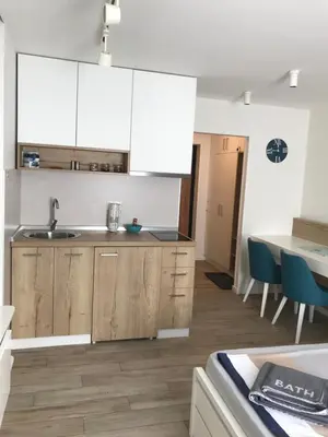 a kitchen with white cabinets and a table with blue chairs at Apartman Relax in Niš