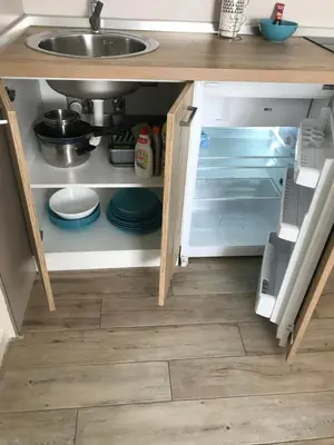 an open kitchen cabinet with a sink and plates at Apartman Relax in Niš