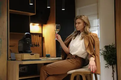 a woman sitting on a chair holding a glass of wine at Design Apartment PLATINIUM SPA LUX 5 STAR 