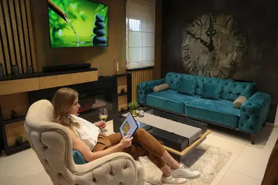 a woman sitting in a chair in a living room with a tablet at Design Apartment PLATINIUM SPA LUX 5 STAR 