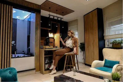 a woman sitting on a stool in a living room at Design Apartment PLATINIUM SPA LUX 5 STAR 