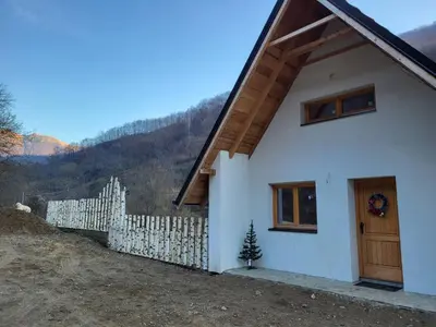 a white house with a wooden door and a fence at Antić apartmani Stara planina in Crni Vrh