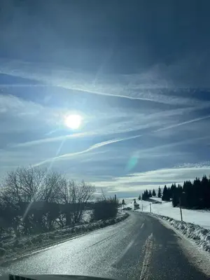 a snow covered road with the sun in the sky at MONTANA apartment 21 in Kopaonik