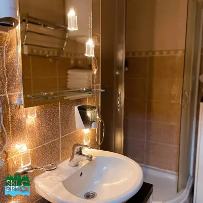 a bathroom with a sink and a shower and a mirror at SKI & SPA Apartment in ZONED in Kopaonik