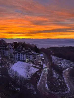 a road in a town with a sunset in the background at Milmari Golden N LUX 62 in Kopaonik