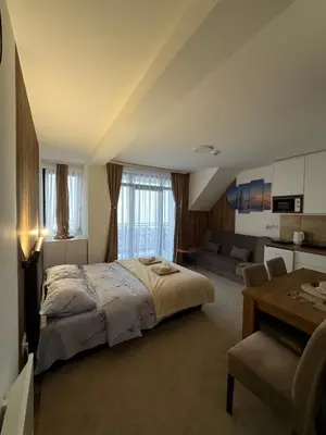 a bedroom with a bed and a living room at Gencian Resort KOPAONIK in Kopaonik