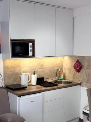 a kitchen with white cabinets and a sink and a microwave at Gencian Resort KOPAONIK in Kopaonik
