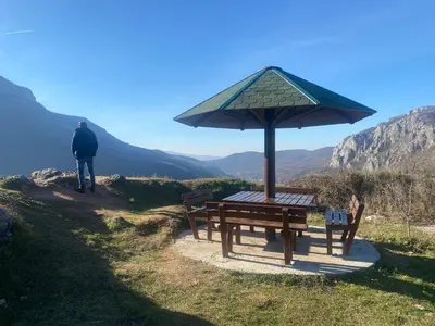a man standing next to a picnic table with an umbrella at Vila Vanilla in Donji Striževac