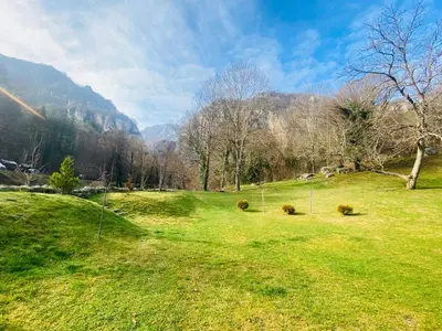 a field of grass with trees and mountains in the background at Vila Vanilla in Donji Striževac