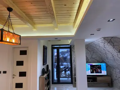 a living room with a ceiling with a stone wall at Apartmani ANA - Kopaonik, Treska in Kopaonik