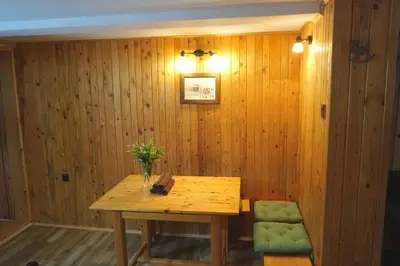 a wooden dining room with a wooden table and a green chair at Montana Apartment in Kopaonik