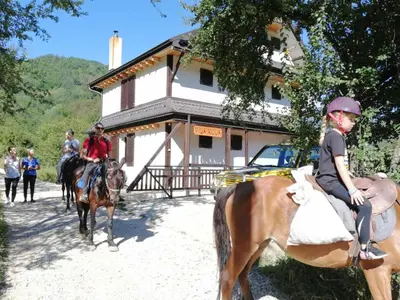 a group of people riding horses in front of a building at Vila Kula in Crni Vrh