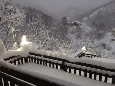 a snow covered yard with two benches covered in snow at Vila Kula in Crni Vrh