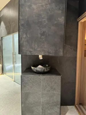 a bathroom with a stone sink on a black wall at Woodside Kopaonik 212 in Kopaonik