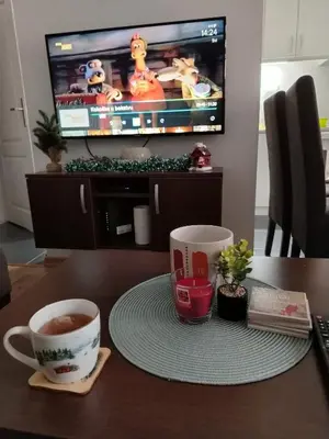 a table with two cups of coffee and a tv at ROSA in Vrnjačka Banja