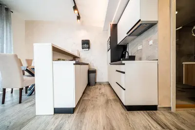 a kitchen with white cabinets and a wooden floor at Vision apartmani Vrnjačka Banja in Vrnjačka Banja