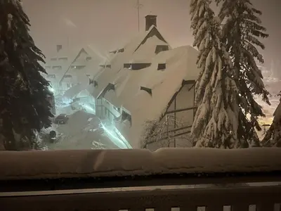 a building covered in snow with trees in the background at Vila Kopaonik Apartmani Milenkovic in Kopaonik