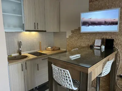 a kitchen with a sink and a counter with chairs at Vila Kopaonik Apartmani Milenkovic in Kopaonik