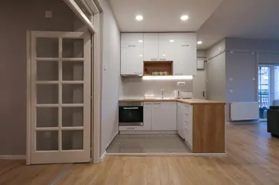 a kitchen with white cabinets and an open door at Heart of Niš Lux in Niš